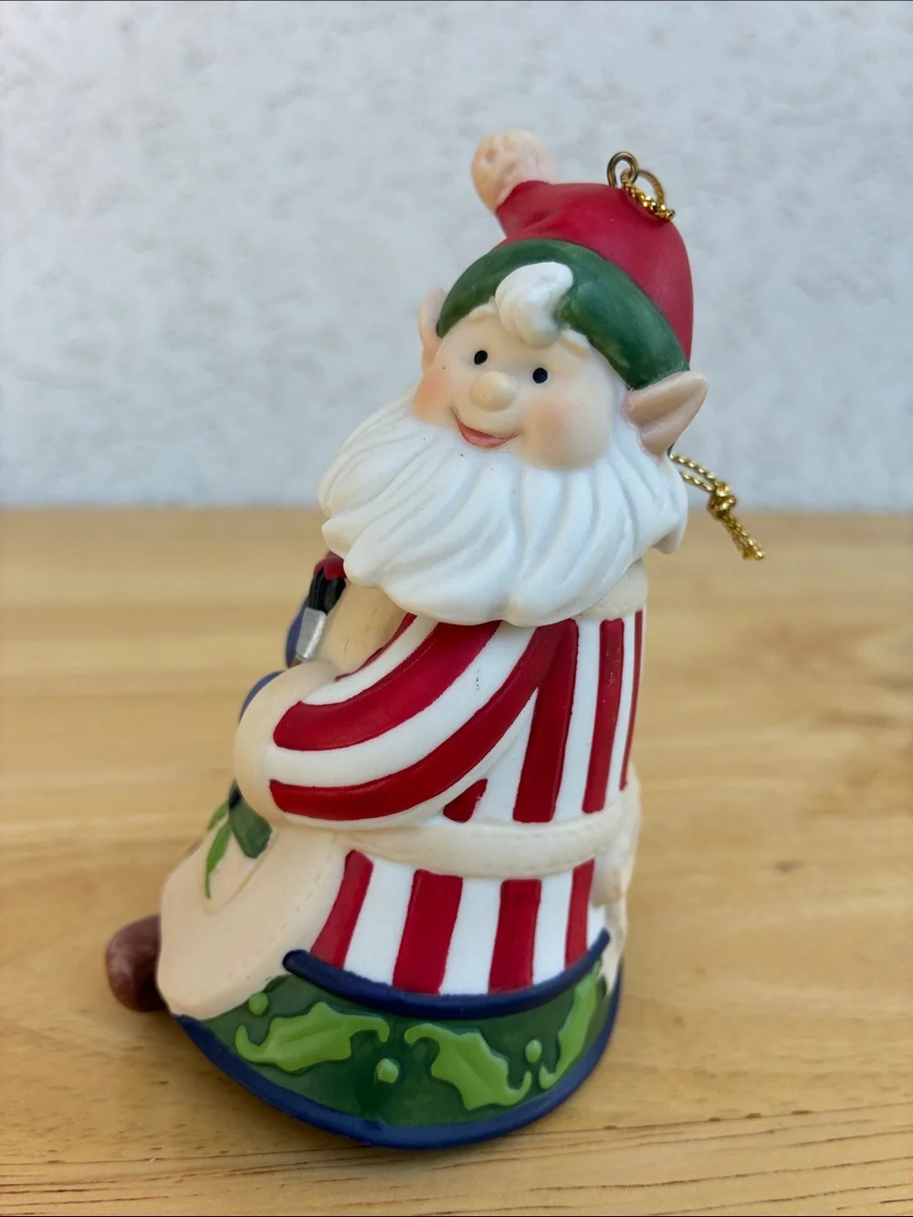 Ceramic elf painting a bird house bell ornament with little floppy legs